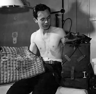 B-17 Flying Fortress waist gunner holding his damaged M1 Flyer’s Vest and parachute pad.