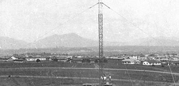 View of the completed radio station from the guard tower. The TRT-22 transmitting modules are in the center of the stacked 55-gallon drum barrier. The 250-foot antenna base is clearly visible. To the left of the photo are the generators and the generator mechanic’s shed.