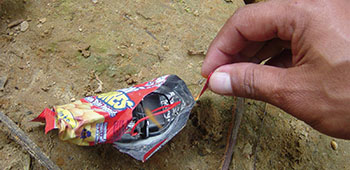 Here a trigger device is hidden inside a discarded potato chip bag, waiting for someone to step on it.