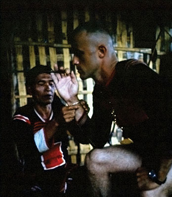 The Shaman puts a copper bracelet on Captain Vernon Gillespie’s wrist to signify brotherhood.