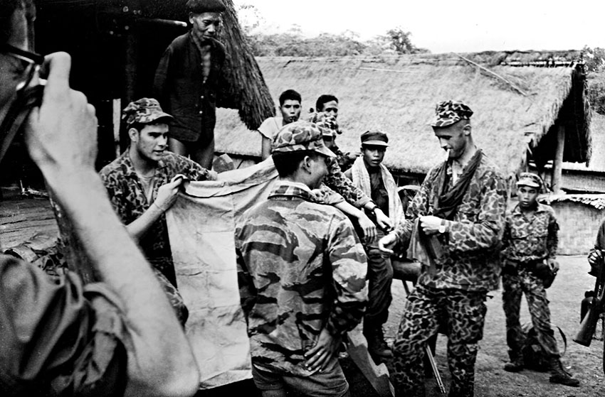 Sergeant Lowell Stevens, holding a captured Viet Cong flag, and Captain Vernon Gillespie  on patrol with some of the Montagnard CIDG.