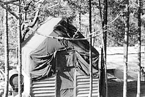 The officer’s quarters in “Paradise Pines” (Pusan), a lone wood-framed tent. The soldiers’ Quonset huts are visible to the rear.