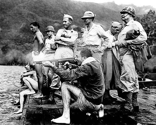 Alamo Scout trainees had to swim an underwater course under fire. Here 1LT Preston Richard fires at the surface with a Thompson sub-machinegun. LTC Frederick Bradshaw, ASTC Director (hands on hips), and MG Innis P. Swift, commander of I Corps (in helmet) observe the training, ASTC Fergusson Island, January 1944.