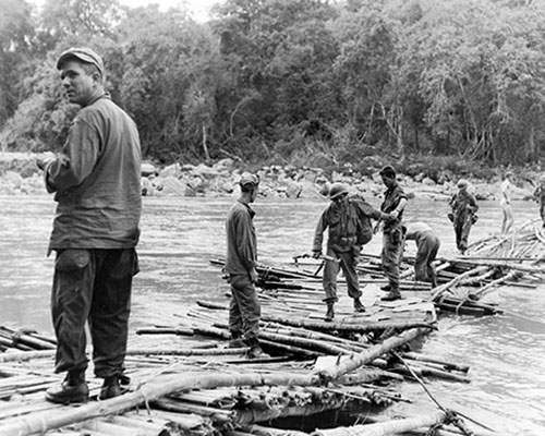 MARSmen cross the swollen Shweli River on 2 March 1945. Soon after, heavy rains threatened to sweep the “bridge” away. Mules were unpacked and led across one at a time while the men carried the supplies.