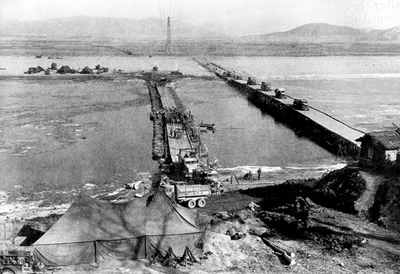 While the Highway Bridge (right) across the Taedong River had been destroyed, U.S. Army engineers quickly erected a pontoon bridge (left) to reconnect East and West P’yongyang until the Highway Bridge could be repaired.
