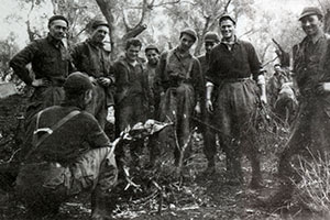 Soldiers roasting a rabbit over an open fire.