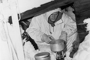 Soldier cooks a warm meal in an improvised dugout.