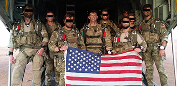 Sgt. Maj. Payne and his teammates prior to a military free fall jump. They hold the American flag to signify duty and devotion to country.
