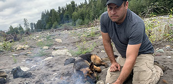 Master Sgt. Earl Plumlee makes coffee from a river with his dog “Pepper”.